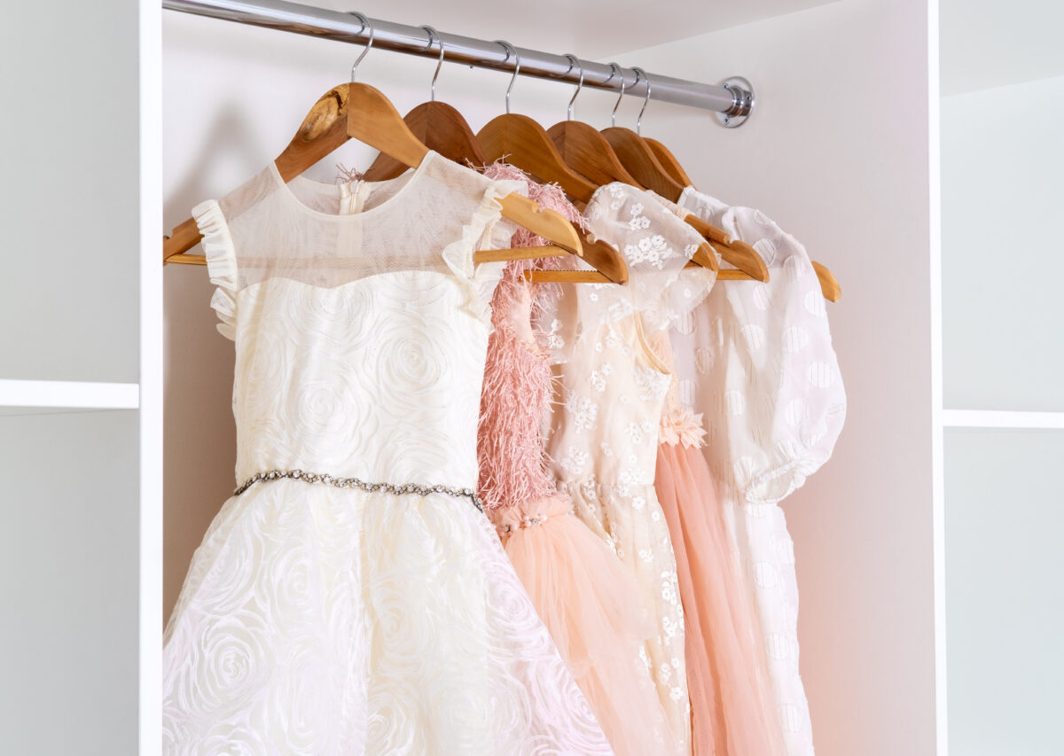 Dresses on hangers in white wardrobe.